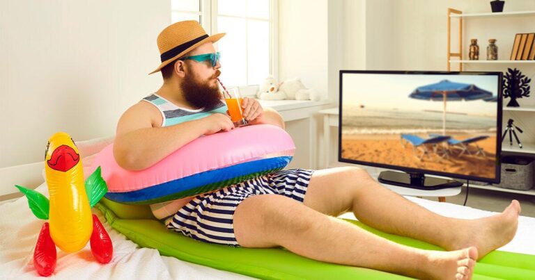 Persona mirando un fondo de pantalla con una playa. Está en su casa vestida de playa.